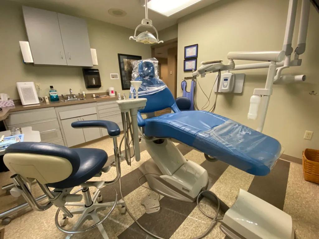 A dental chair in a room with a sink and other equipment.