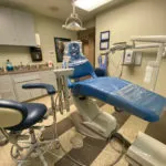 A dental chair in a room with a sink and other equipment.