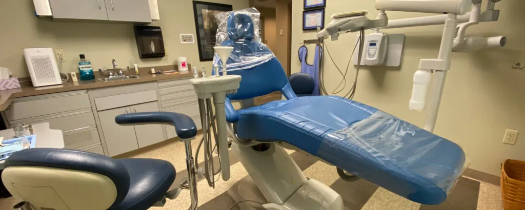 A dental chair in a room with a sink and other equipment.