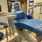 A dental chair in a room with a sink and other equipment.